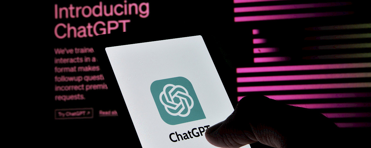 Eine Person hält ein Smartphone in der Hand, auf dessen Bildschirm das ChatGPT-Logo angezeigt wird